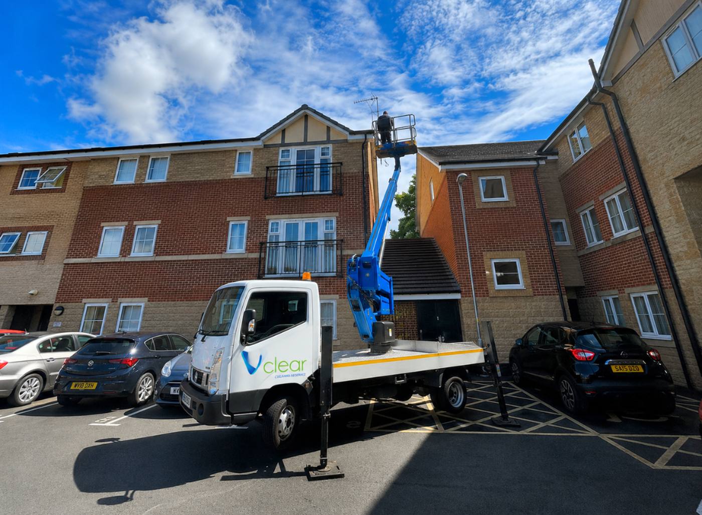 Vclear operative using a cherry picker to clean windows on a residential block